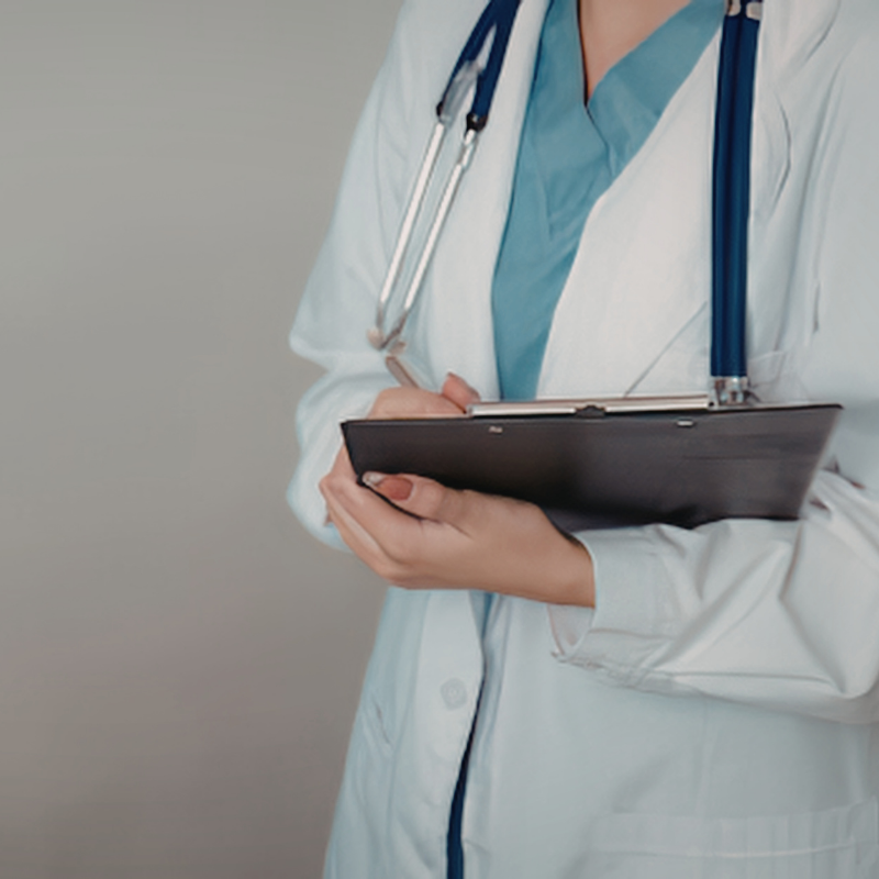 Doctor holding a clipboard with a neutral background
